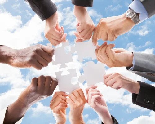 Directly below shot of multiethnic business people assembling jigsaw puzzle against sky
