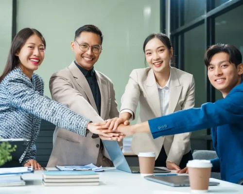 In a boardroom, an Asian team meets at a desk, presenting financial terms and strategies.